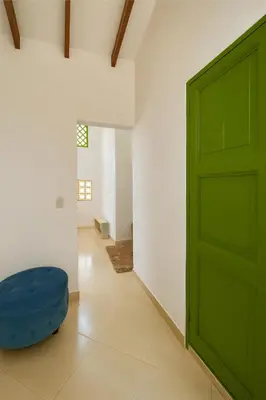 a green door in a white room with a blue stool at Aluna Apartamento Jericó in Jericó
