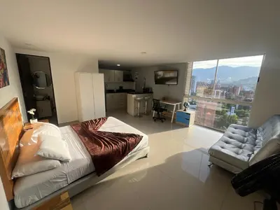a bedroom with a bed and a couch and a kitchen at Loft en Medellin El Poblado Vista espectacular in Medellín