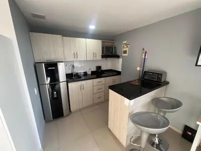 a small kitchen with a black counter and a refrigerator at Loft en Medellin El Poblado Vista espectacular in Medellín