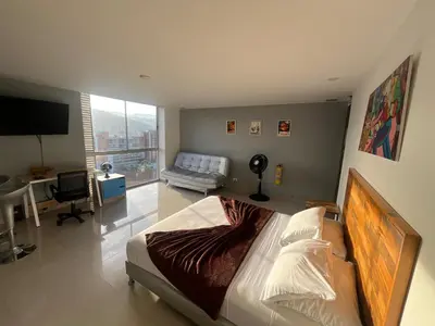 a bedroom with a bed and a desk and a television at Loft en Medellin El Poblado Vista espectacular in Medellín