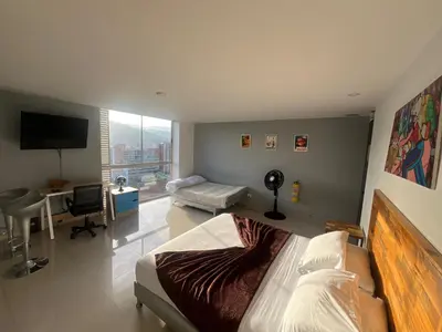 a bedroom with a bed and a desk and a television at Loft en Medellin El Poblado Vista espectacular in Medellín