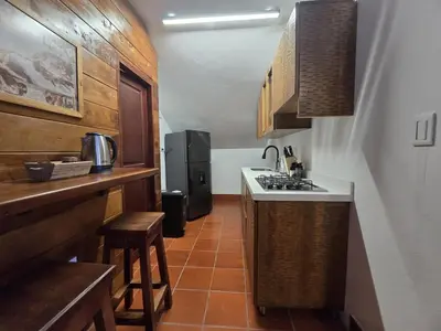 a small kitchen with a stove and a refrigerator at Luxurious country cabin, BBQ, Jacuzzi, TV, WiFi in Marinilla