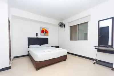 a white bedroom with a bed and a television at Hotel Villa Real 70 Laureles in Medellín