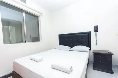 a white bedroom with a large bed and a window at Hotel Villa Real 70 Laureles in Medellín