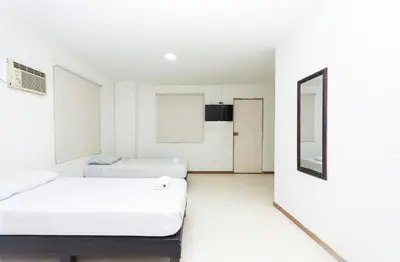 two beds in a white room with a mirror at Hotel Villa Real 70 Laureles in Medellín