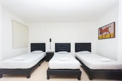 three beds in a room with white walls at Hotel Villa Real 70 Laureles in Medellín
