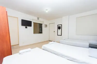 two beds in a room with a tv on the wall at Hotel Villa Real 70 Laureles in Medellín