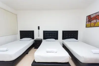 three beds in a room with white walls at Hotel Villa Real 70 Laureles in Medellín