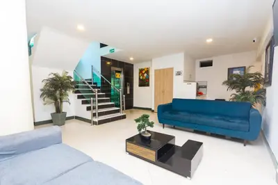 a living room with a blue couch and a staircase at Hotel Villa Real 70 Laureles in Medellín