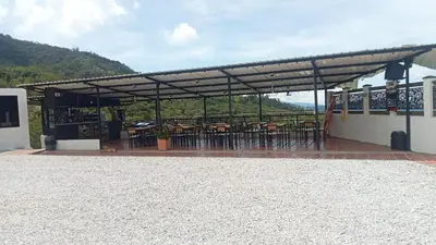 a patio with tables and chairs under a roof at Hotel Curazao Natural Living cerca a charcos naturales y tobogán extremo in Cocorná