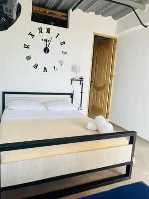a bedroom with a bed and a clock on the wall at Hotel Curazao Natural Living cerca a charcos naturales y tobogán extremo in Cocorná