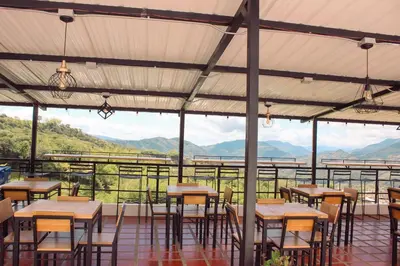 a restaurant with tables and chairs and mountains in the background at Hotel Curazao Natural Living cerca a charcos naturales y tobogán extremo in Cocorná