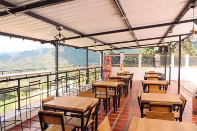 a restaurant with tables and chairs on a balcony at Hotel Curazao Natural Living cerca a charcos naturales y tobogán extremo in Cocorná