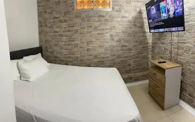 a bedroom with a bed and a tv on a brick wall at Apartamento en la mejor zona de buenos aires in Medellín