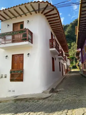 a white building with wooden doors and balconies on a street at Casa Colonial Jericó - Casa Romo in Jericó