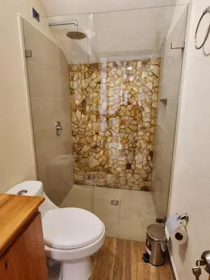 a bathroom with a toilet and a stone wall at Casa Colonial Jericó - Casa Romo in Jericó