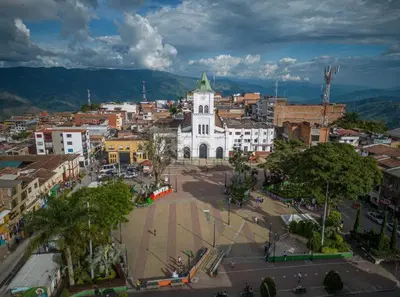 a large white building with a clock tower in a city at Hotel Galería Plaza in Santa Bárbara