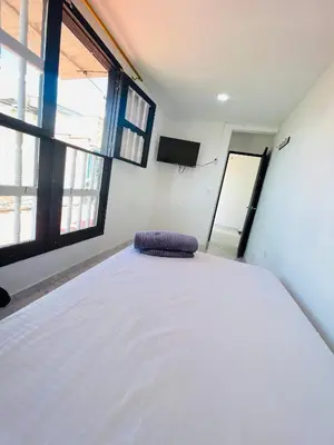 a white bed in a room with a large window at Hospedaje Mi casita in Guatapé