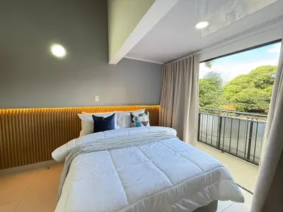 a bedroom with a large bed and a balcony at Laureles Boutique Stay in Medellín