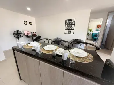 a kitchen with a table with plates and glasses on it at Apartamento con vista a la montaña, piscina y gym in Sabaneta