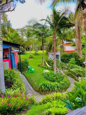 a garden with palm trees and flowers and a building at Hotel Marrokos Aeropuerto José María Córdova in Rionegro