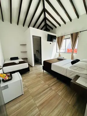 two beds in a large room with wooden floors at Hotel Paraiso Cañaveral in Santa Fe de Antioquia