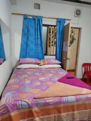a bed with blue curtains and a colorful comforter at Hospedaje Bonanza in Santa Fe de Antioquia