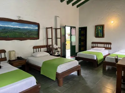 a bedroom with three beds with green and white sheets at Hotel Vegas del Rio in Támesis