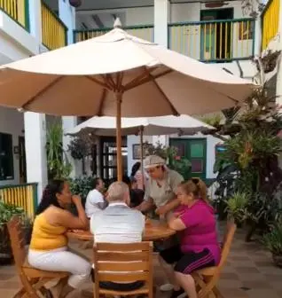 a group of people sitting at a table under an umbrella at Hotel Vegas del Rio in Támesis