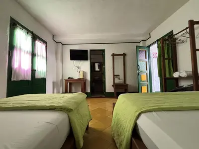 a room with two beds with green sheets on them at Hotel Vegas del Rio in Támesis