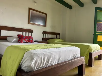 two beds in a room with green and white at Hotel Vegas del Rio in Támesis