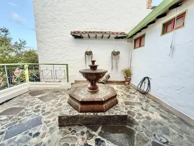 a stone patio with a fountain in front of a building at Elegant Colonial Walkable Casa in Jericó