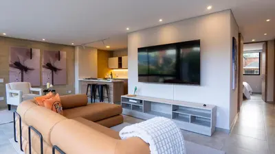 a living room with a couch and a tv on a wall at 99Rentall in Medellín