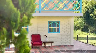 a red chair and a table in front of a building at Casa de 7 habitaciones cerca al pueblo de Guatapé in Guatapé