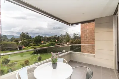 a balcony with a white table and chairs and a large window at aparta hotel campestre luxury en llanogrande 10 minutos aeropuerto in Rionegro