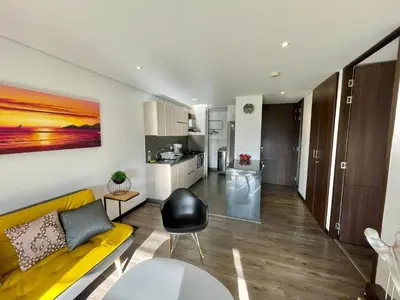 a living room with a yellow couch and a kitchen at aparta hotel campestre luxury en llanogrande 10 minutos aeropuerto in Rionegro