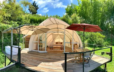 a yurt with a bed and two umbrellas on a wooden deck at Moonshine - Sereno Glamping in Manizales