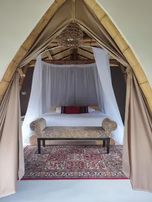 a canopy bed with a bench in a tent at Leaf House - Sereno Glamping in El Tablazo