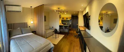 a bedroom with a bed and a living room at Premium Studio near Oviedo Mall, El Poblado- Balcony, AC & Fast WiFi in Medellín