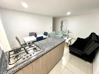 a kitchen with a stove and a living room at Espectacular apartamento in Manizales