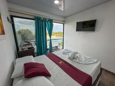 a bedroom with a bed and a window with a view at HOTEL COLONIAL santorini colombiano in Doradal