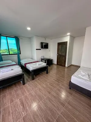 a large room with two beds and a television at HOTEL COLONIAL santorini colombiano in Doradal
