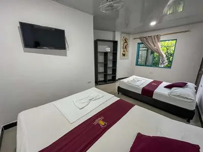 a bedroom with two beds and a flat screen tv at HOTEL COLONIAL santorini colombiano in Doradal