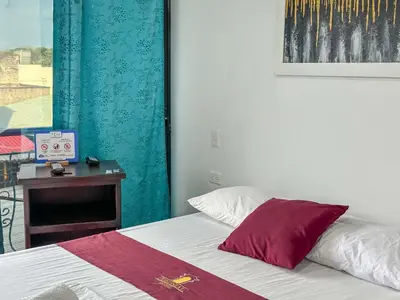 a bedroom with a bed and a table with a clock at HOTEL COLONIAL santorini colombiano in Doradal