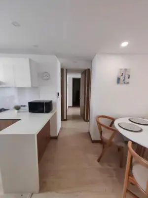 a kitchen with white counters and a table and chairs at Modern and Cozy Las Camelias in Manizales