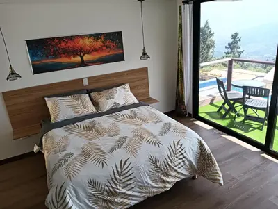 a bedroom with a bed and a balcony with a table at VIVE PARADISE - UNICA HOSTERIA TERMAL Only Adult a solo 15 minutos de la ciudad in Medellín