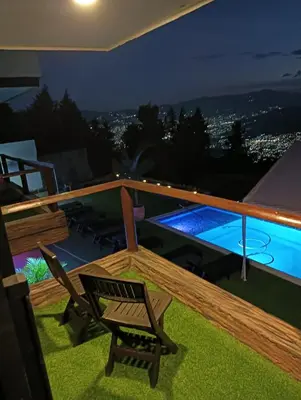 a deck with a chair and a swimming pool at night at VIVE PARADISE - UNICA HOSTERIA TERMAL Only Adult a solo 15 minutos de la ciudad in Medellín