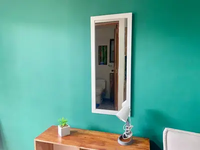 a room with a green wall and a mirror on a table at Estudio renovado Belén, ubicación e iluminación in Medellín