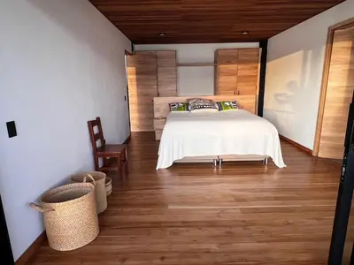 a bedroom with a white bed and a wooden floor at Villa de lujo frente a la represa del Peñol in El Peñol
