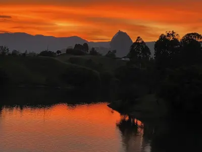 a sunset over a river with a mountain in the background at Villa de lujo frente a la represa del Peñol in El Peñol